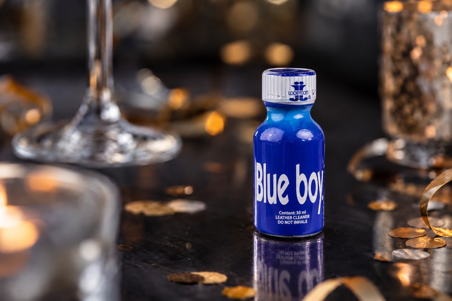 Mini flacon bleu intitulé “Blue boy” posé sur une surface sombre avec décorations dorées et feutrines, sur fond flou.