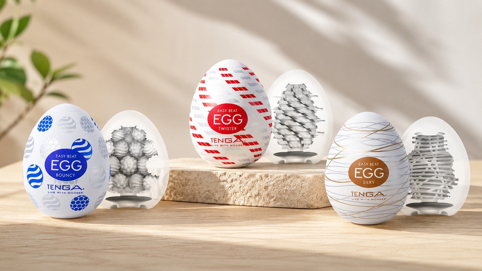 Œufs de massage Tenga Eggs en lot sur planchette en bois, motifs géométriques bleus et rouges, décor minimaliste.